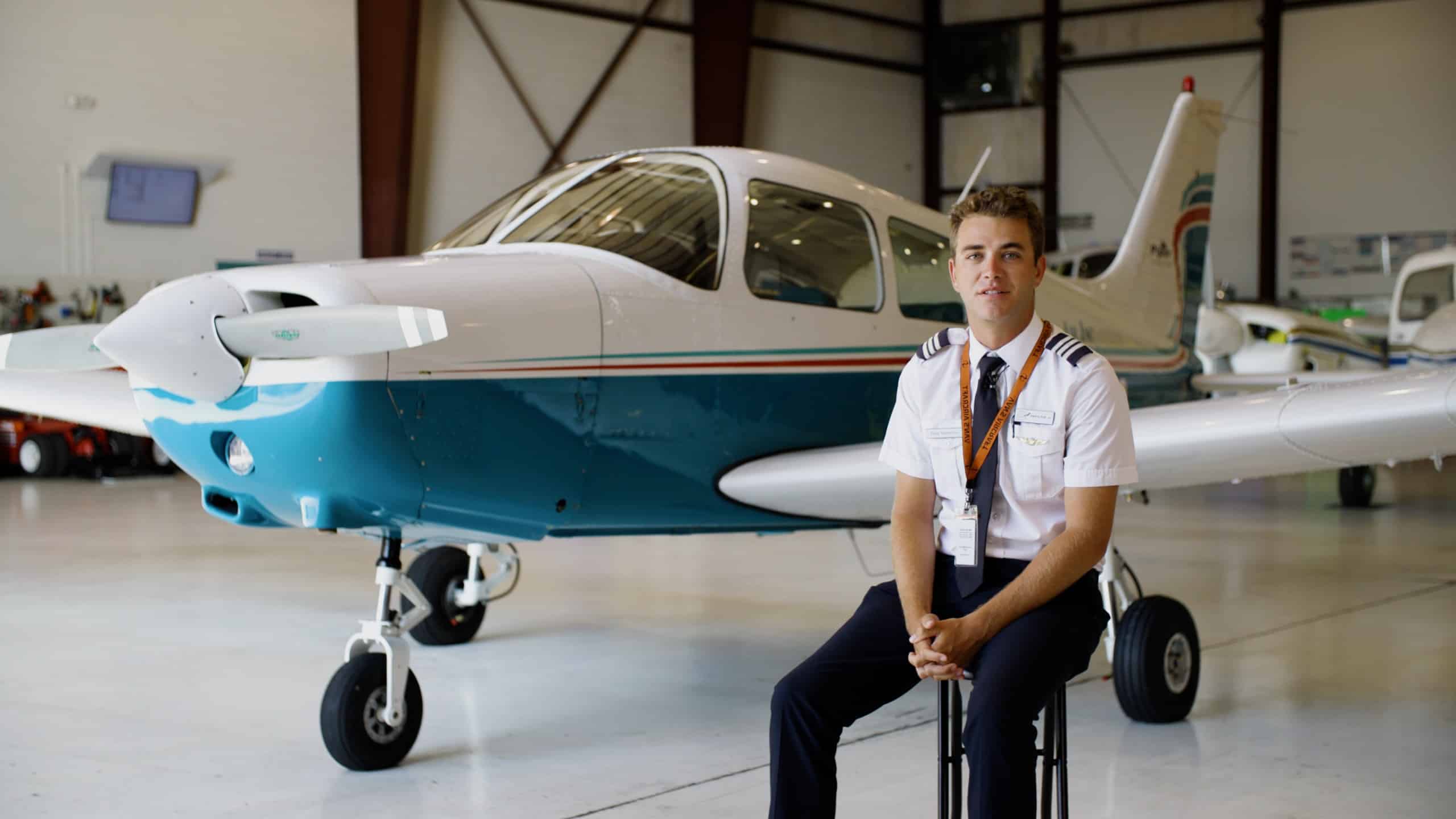 A Paris Air instructor sitting in front of a small airplane, looking at the camera