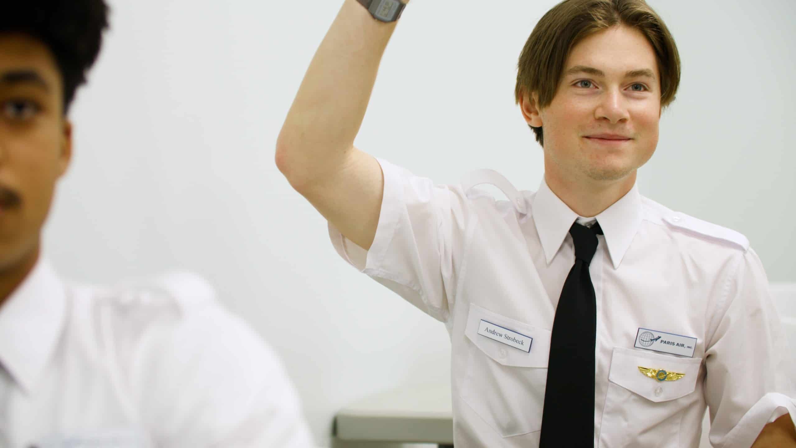 A Paris Air flight student raising his hand, with another student in the foreground