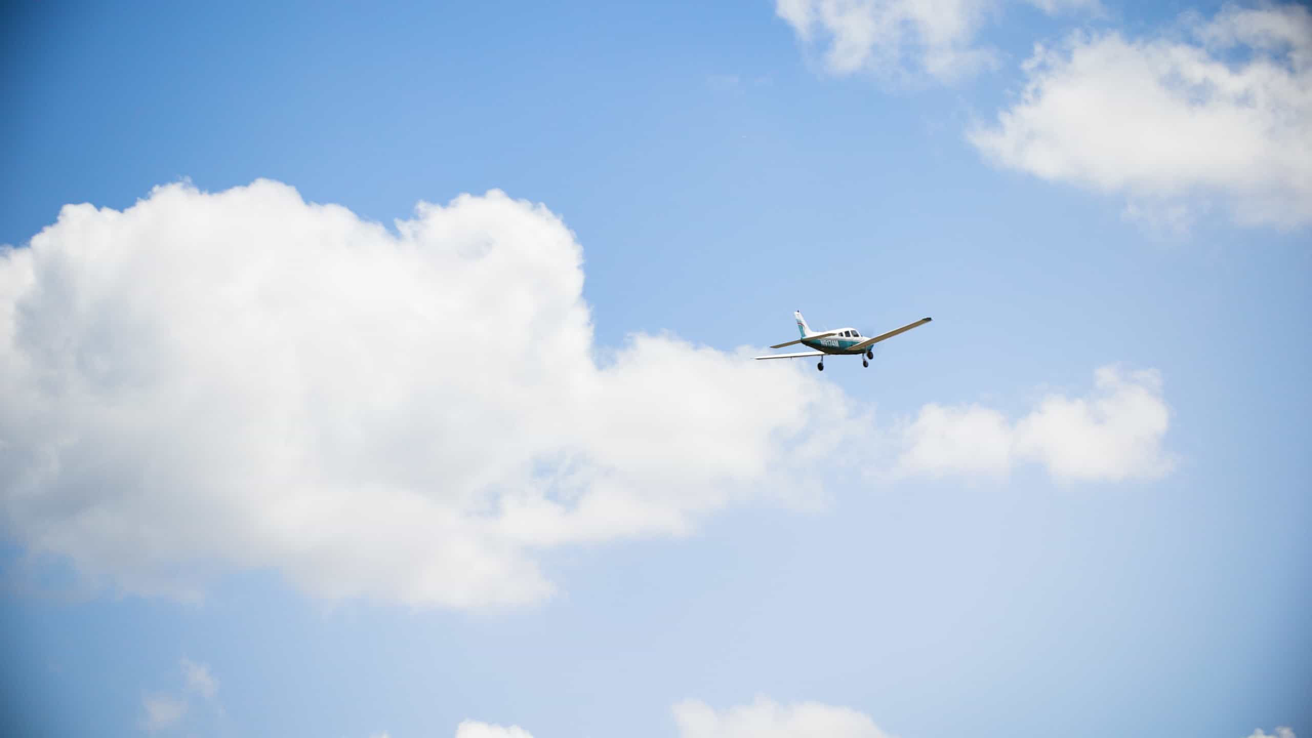 Small airplane flying against a blue sky with white clouds