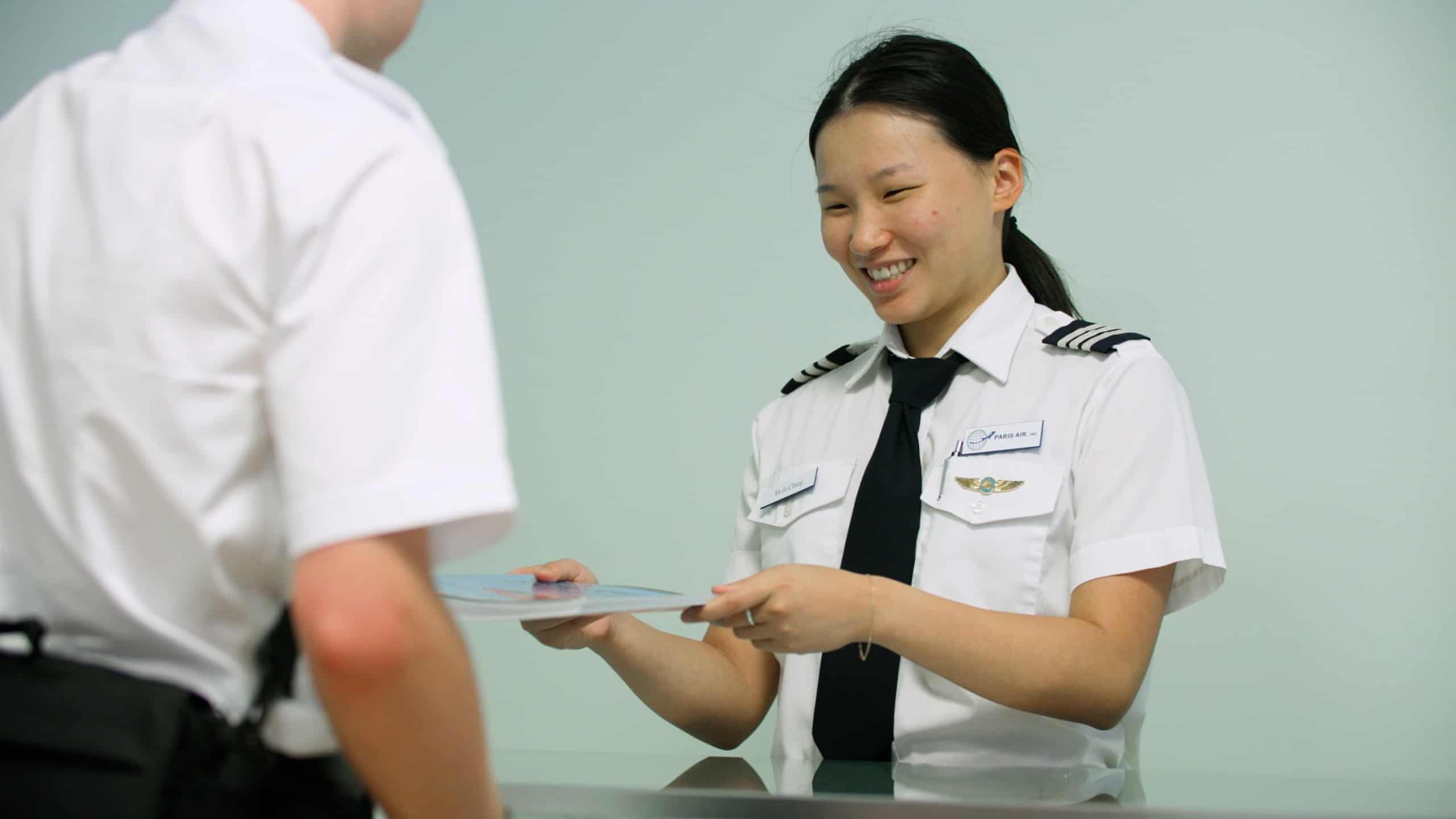 A clerk at the Paris Air Pilot Shop handing a book to a flight student