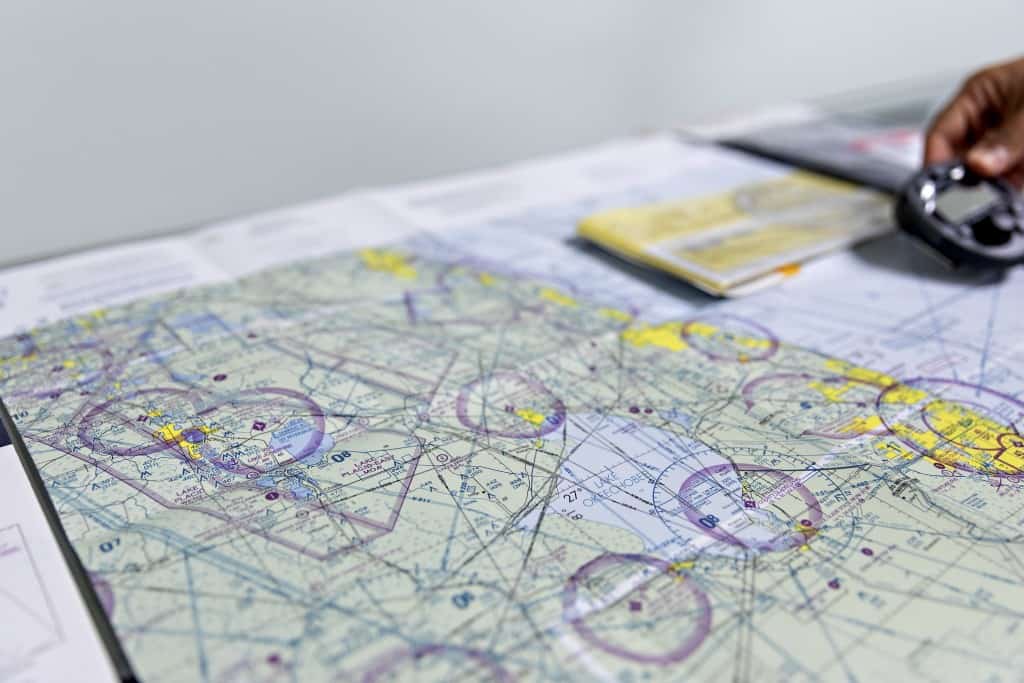 Photo of navigation chart with a hand holding a navigation instrument