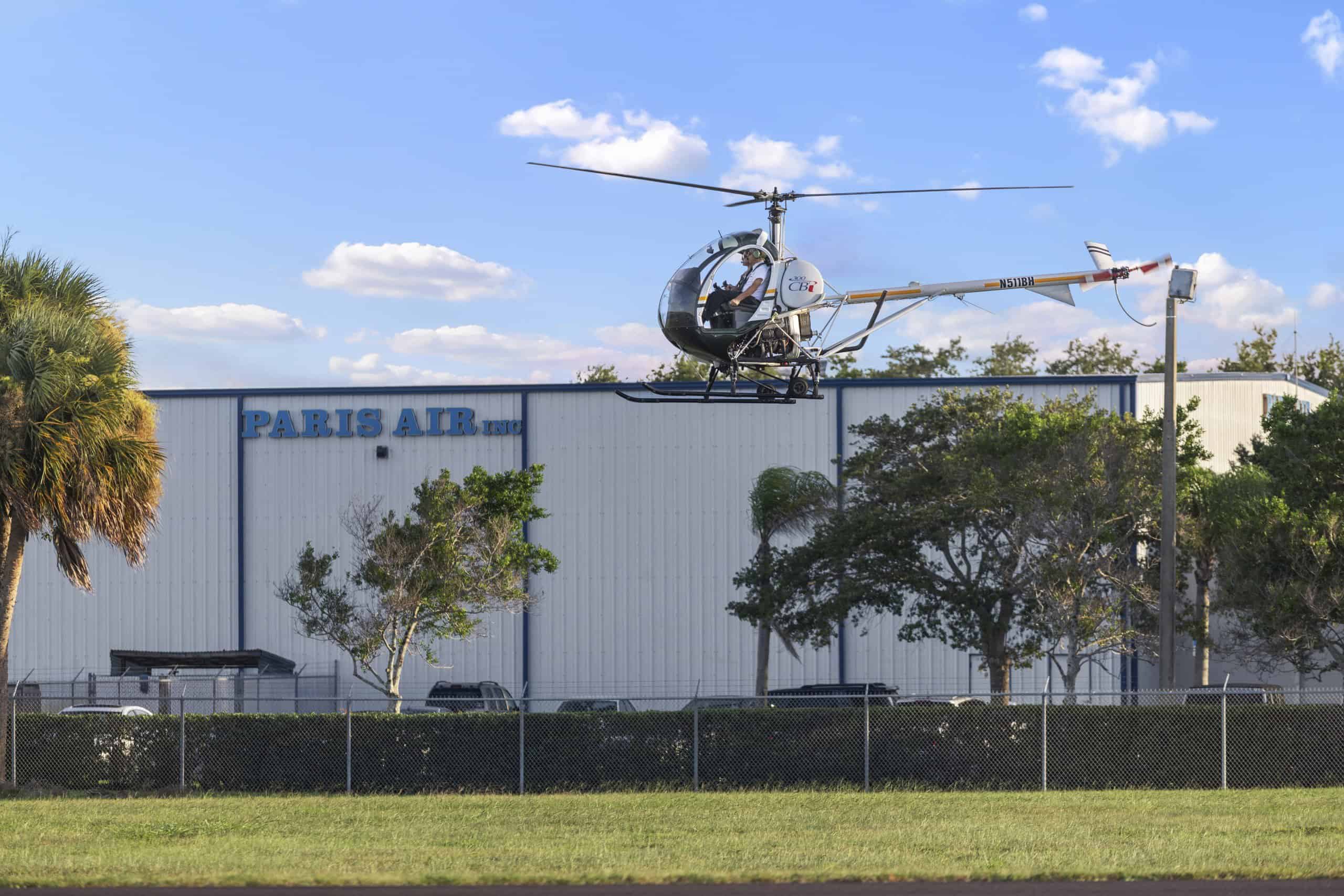 Photo of a helicopter in the air in front of the Paris Air building