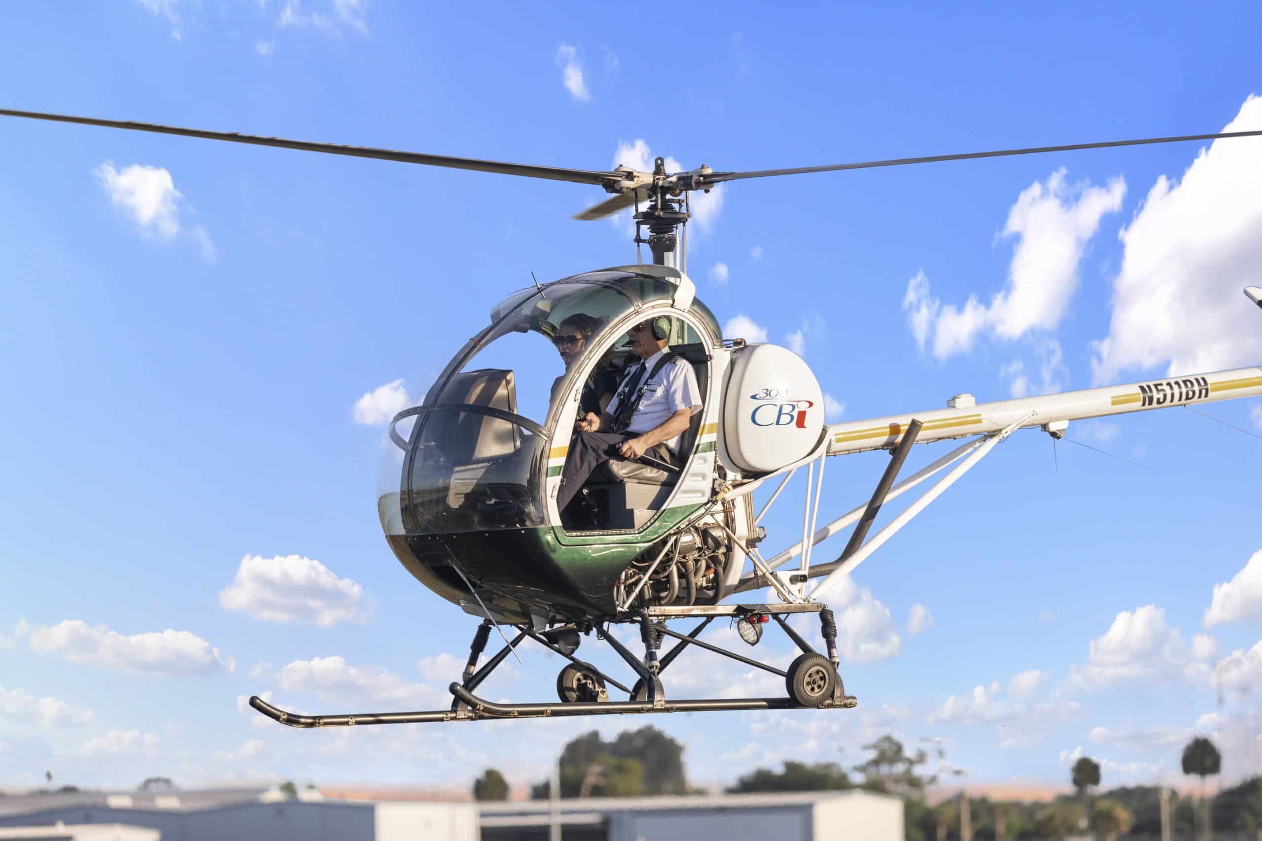 Photo of a helicopter hovering over a building with blue sky and white clouds in the background